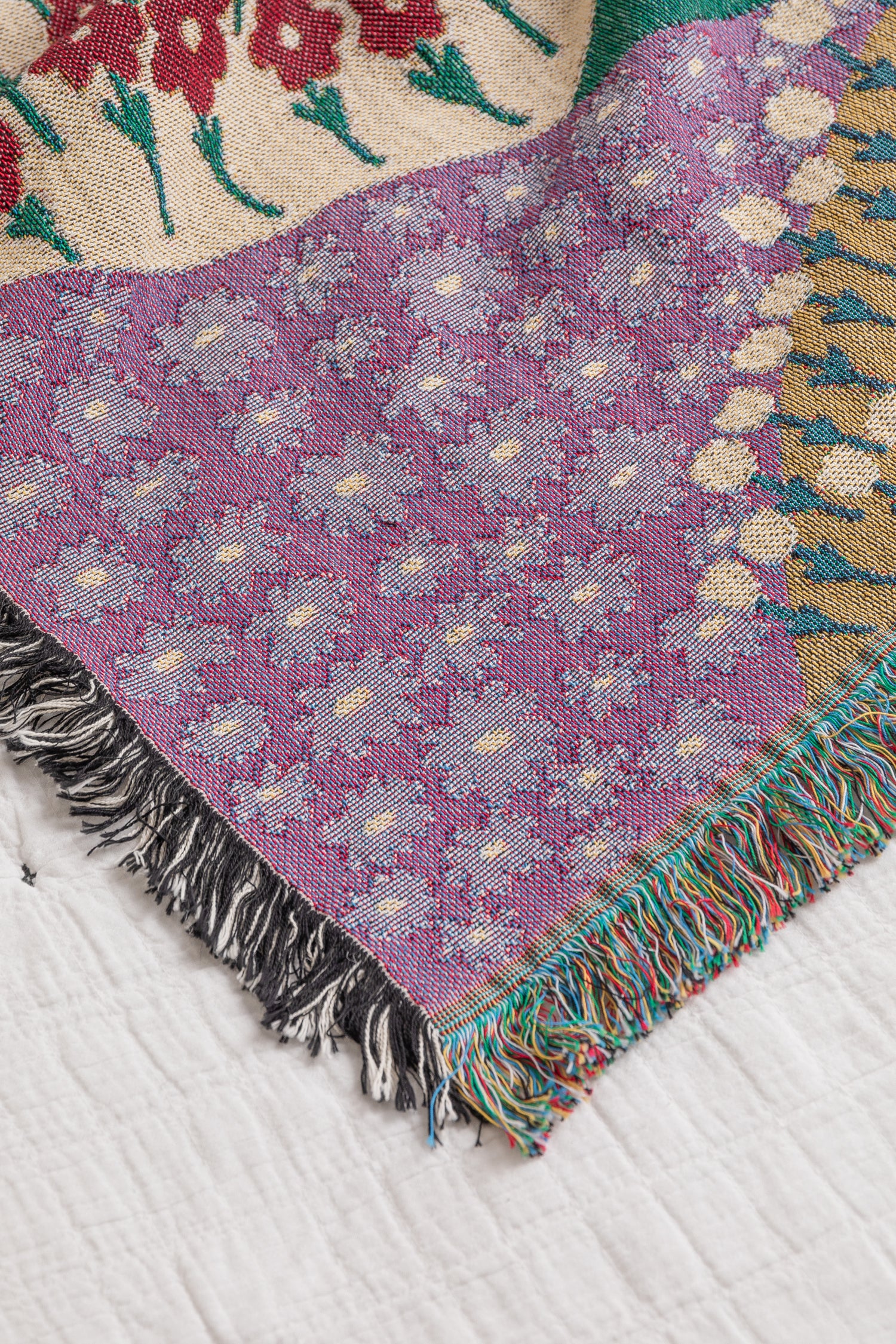 Colorful woven throw blanket with a floral pattern and geometric designs with a fringe border