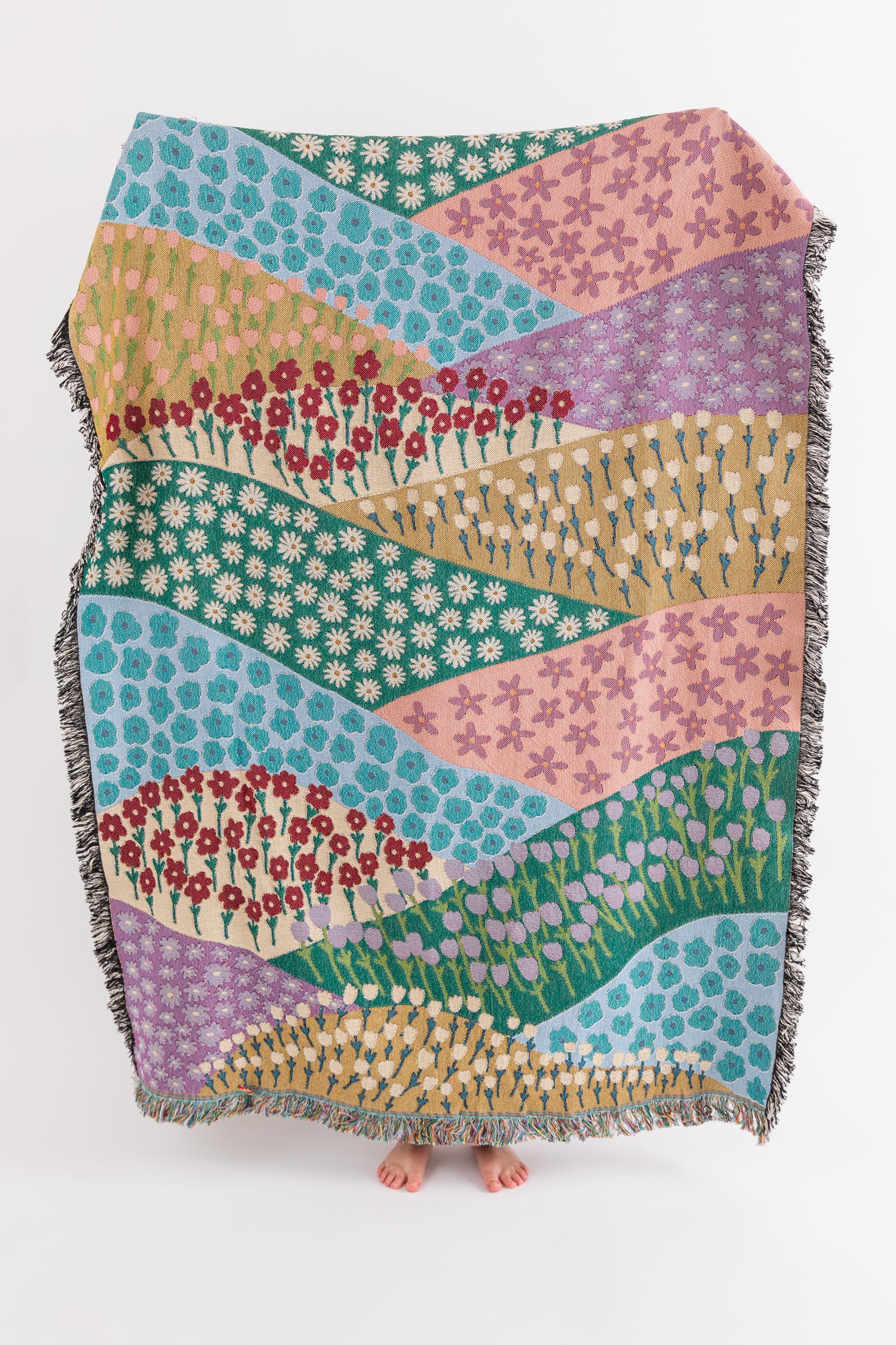 Colorful woven throw blanket with a floral pattern and geometric designs with a fringe border