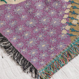 Colorful woven throw blanket with a floral pattern and geometric designs with a fringe border
