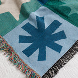 Colorful blanket with geometric patterns on a white bedspread.