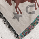 Blanket with horse and horseshoe pattern on a white bedspread