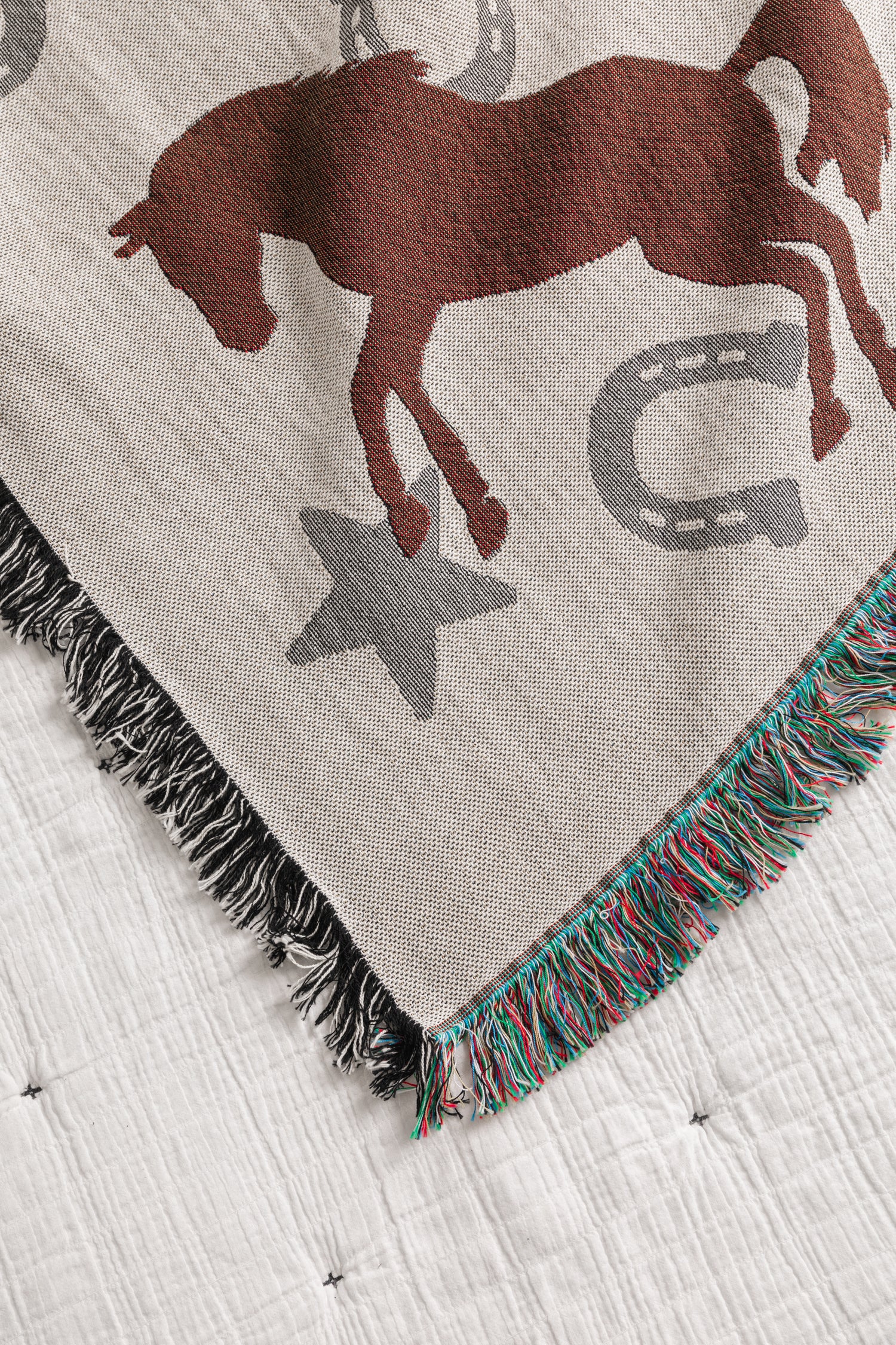 Blanket with horse and horseshoe pattern on a white bedspread